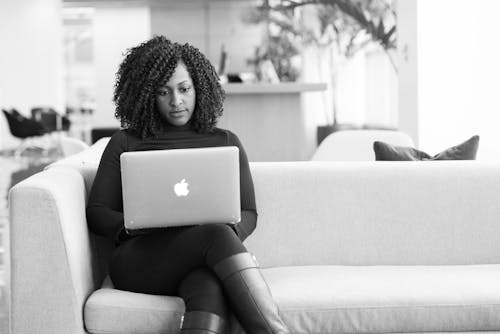 Woman Sitting on Couch Using Macbook