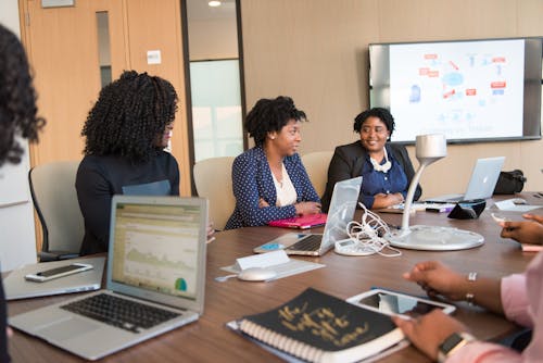 Free Women Gathered on Table Near Monitor Stock Photo