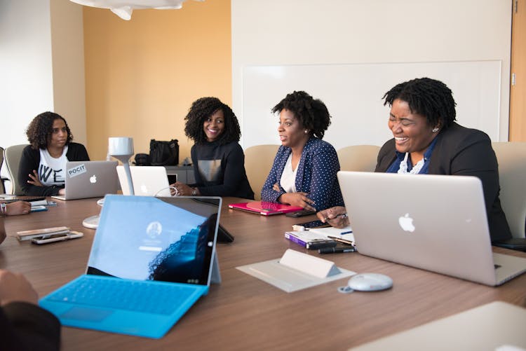 Group Of People Talking To Each Other In Front Of Brown Wooden Table