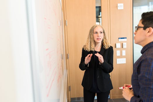 Two professionals engaged in a business discussion in a well-lit modern office space.