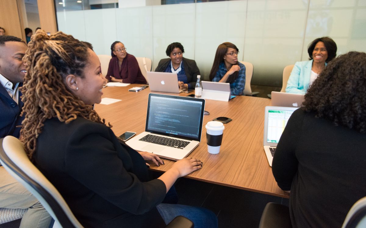 A diverse group of professionals working together in a modern conference room with laptops.