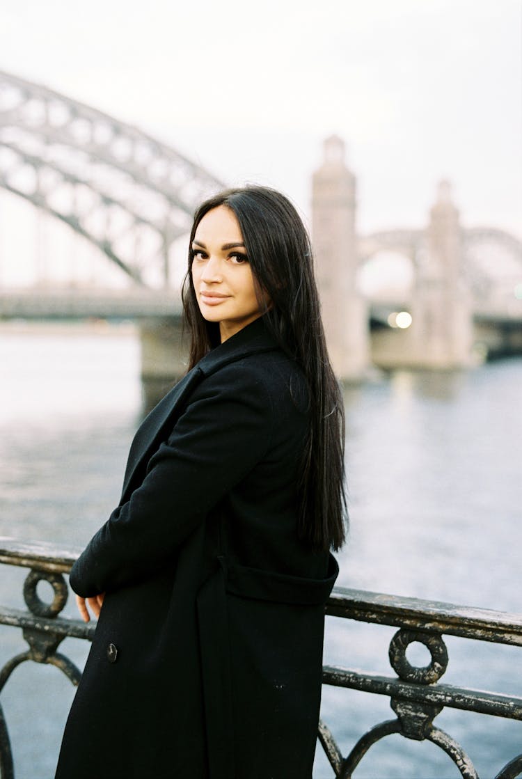 Woman Leaning On Bridge Railing Looking Over Shoulder