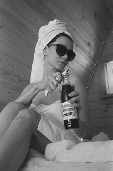 Woman relaxing in towel with soda and sunglasses, monochrome setting.