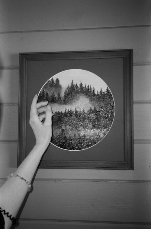 Grayscale Photo of a Person Holding a Mirror