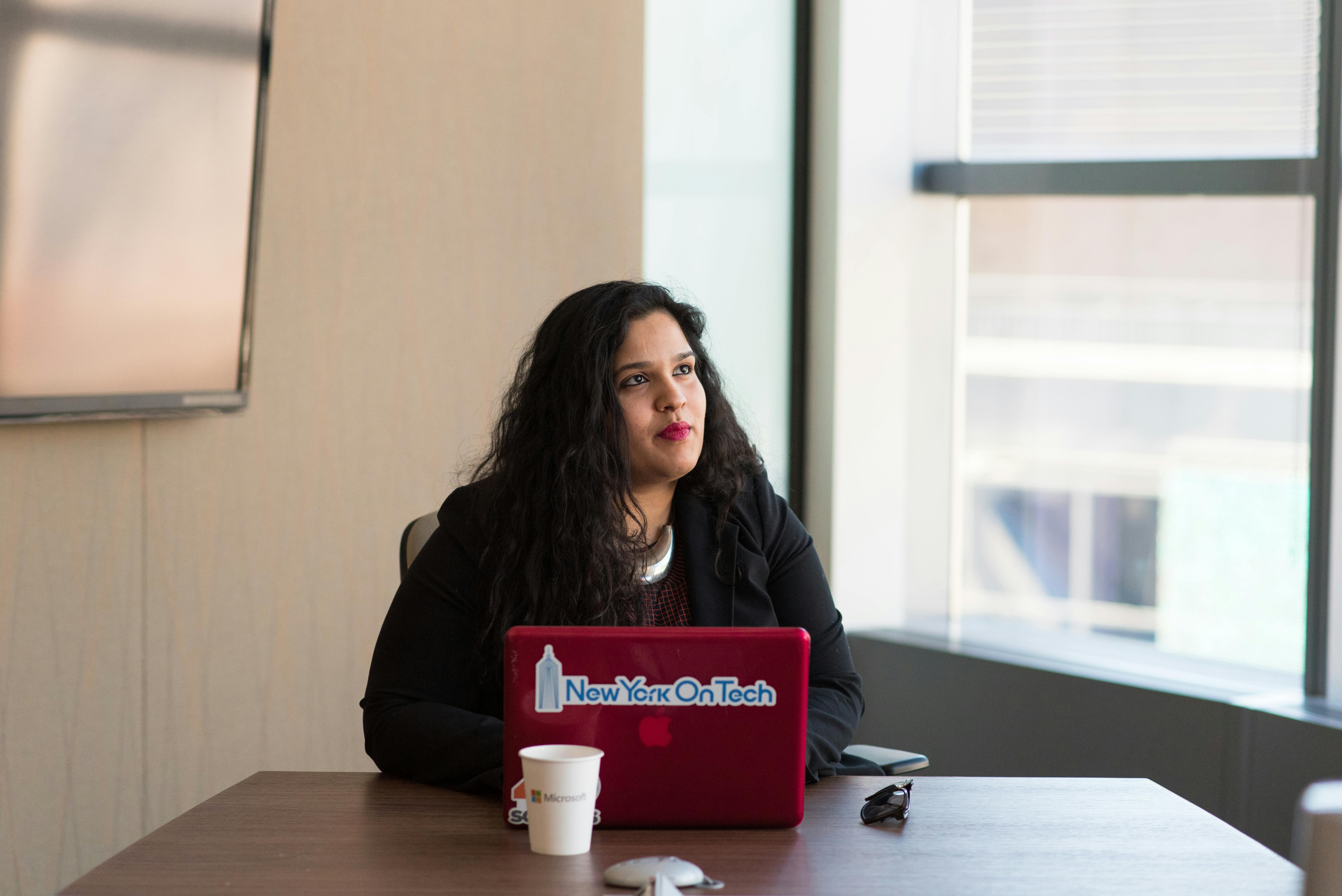 woman wearing black long sleeved shirt using red macbook