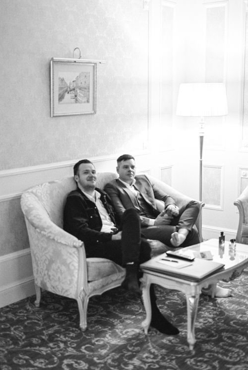 Free Two men relax in a luxurious hotel lounge, seated on an elegant sofa. Black and white photo. Stock Photo