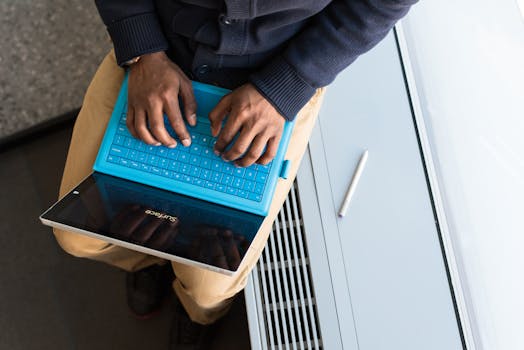 A person typing on a tablet with a blue keyboard indoors, highlighting remote work.