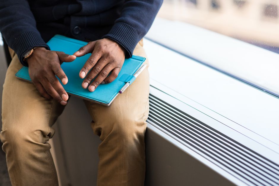 Focused man holding tablet by a bright office window, ready for work.
