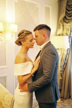 Bride and groom sharing an intimate moment on their wedding day in a softly lit room.
