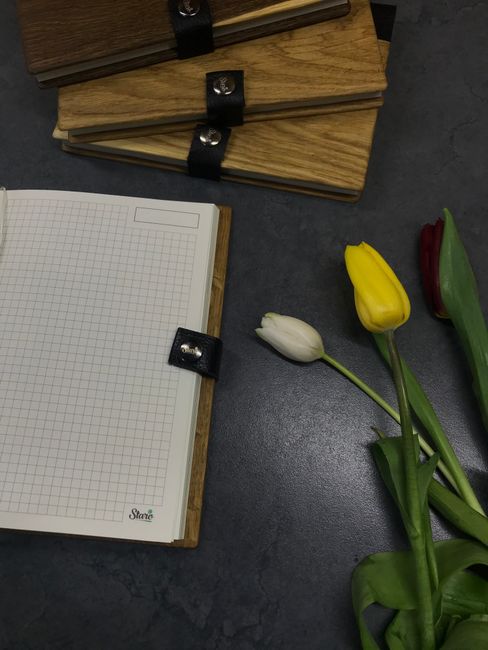 Fotomural Tulipanes coloridos con un cuaderno abierto sobre una superficie oscura, perfecto para conceptos de papelería.