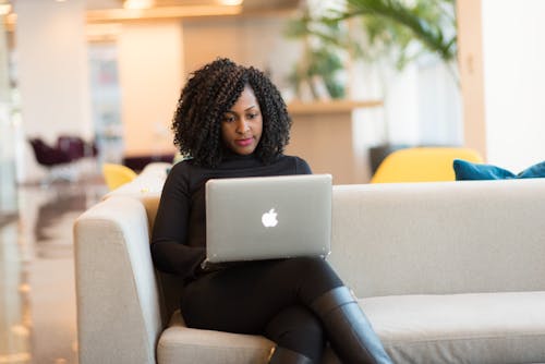 Free Woman Using Macbook Sitting On White Couch Stock Photo