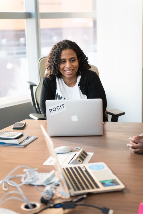 Free Cheerful woman using laptop in a modern workspace setting. Stock Photo