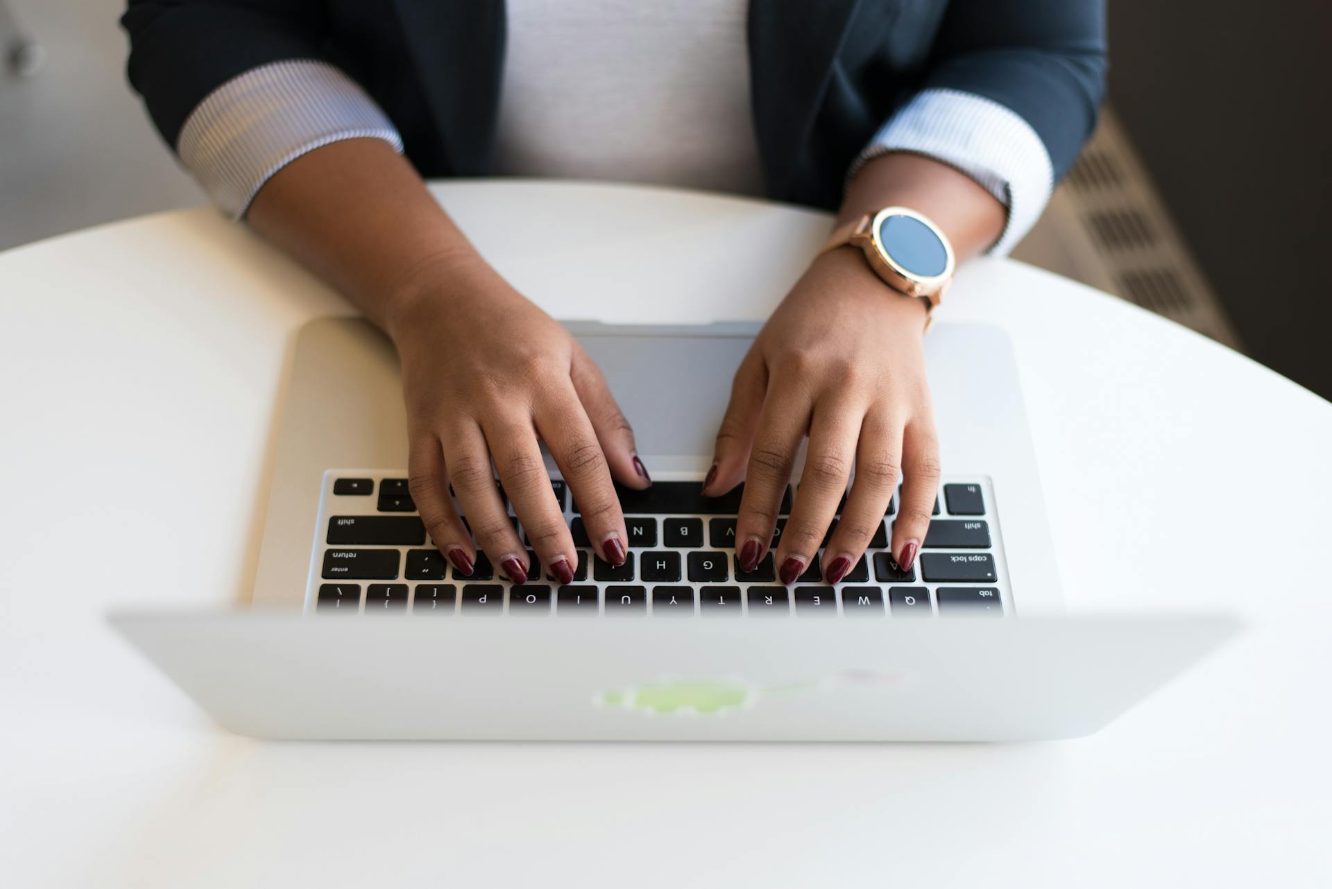 Woman's hands typing on a wireless laptop at a modern office desk, highlighting technology in business.