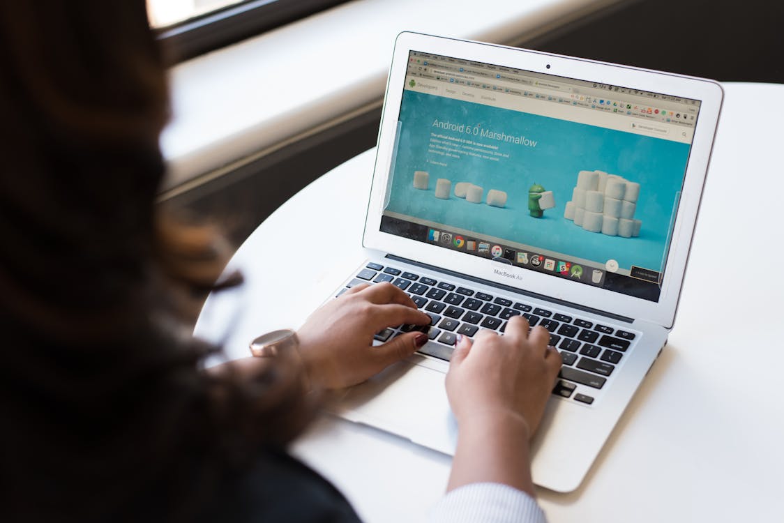 Free Woman Sitting Near Table Using Macbook Stock Photo