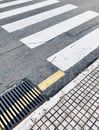 Crosswalk marked on asphalt road near sewer grid in city