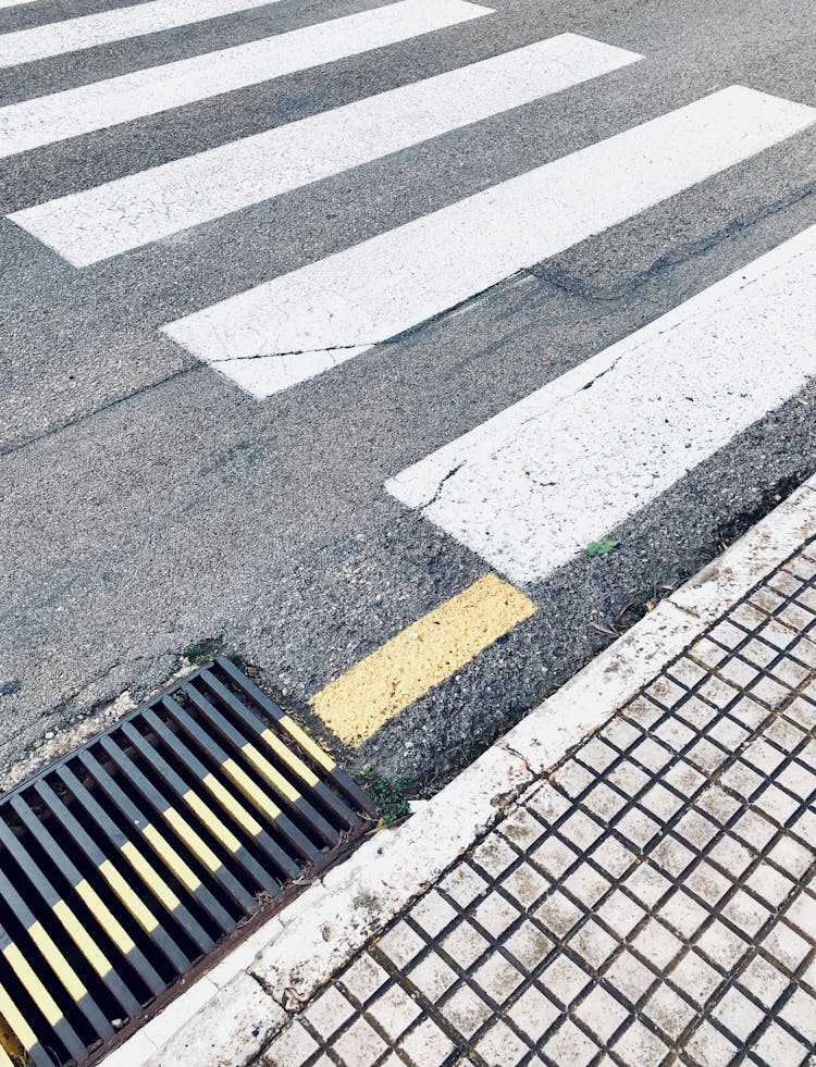 Crosswalk Marked On Asphalt Road Near Sewer Grid In City