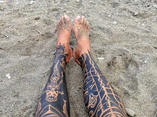 Free Tattoo Legs Relaxing on Beach Stock Photo