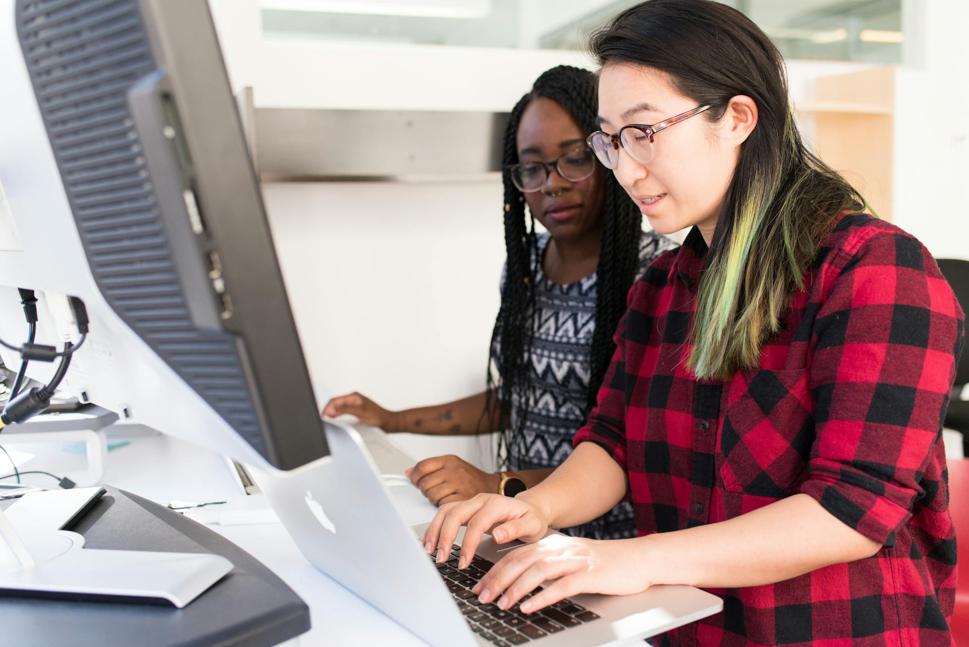 Two female developers collaborating on a project in a modern office setting.