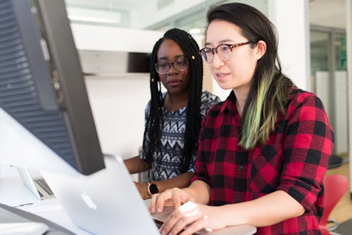 Macbookを使用して赤と黒の市松模様のブラウスを着ている女性