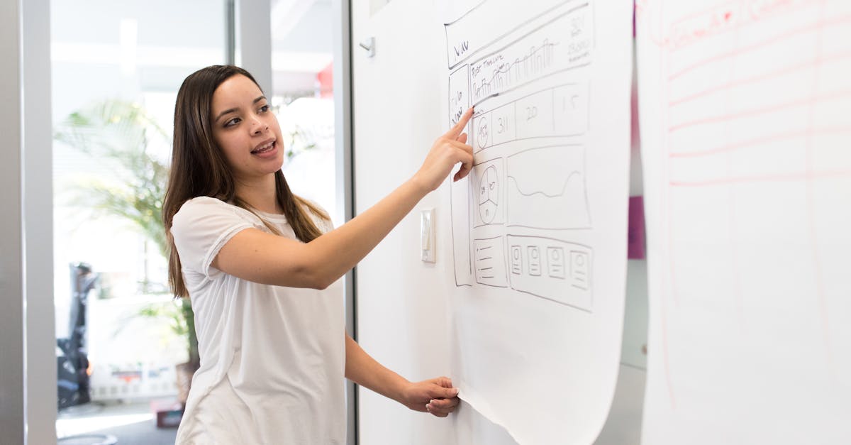 Woman Wearing White Shirt Standing Beside White Board While Pointing on White Paper