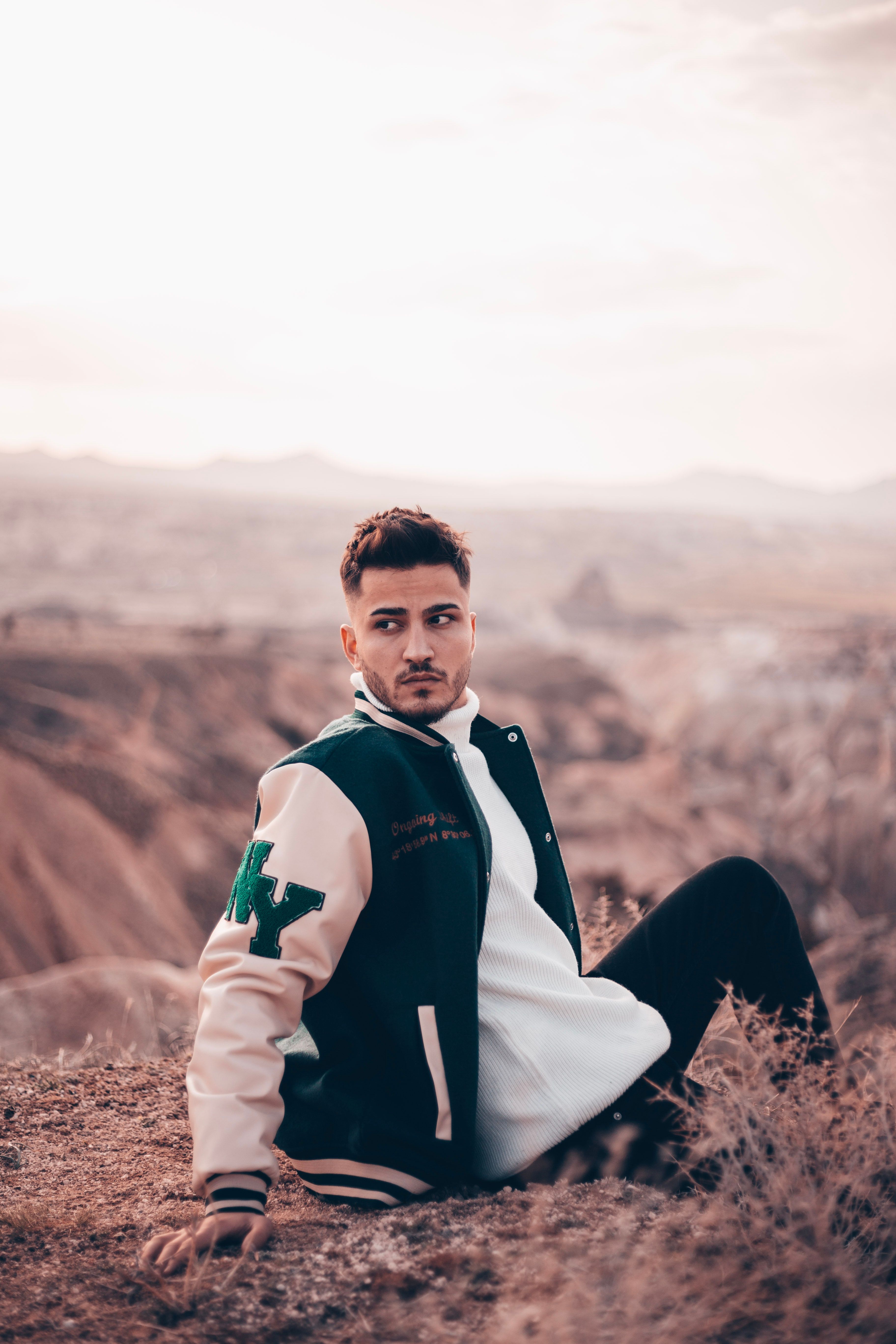 Fashionable young man wearing a jacket poses against scenic outdoors in Türkiye.
