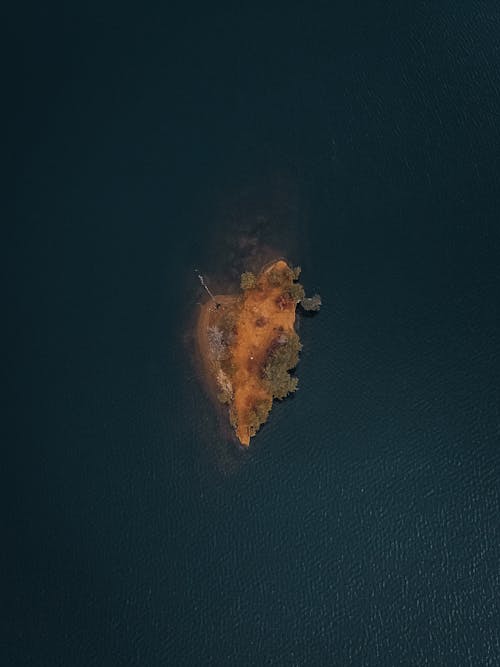 Free Aerial photo capturing the serene beauty of a small island surrounded by tranquil waters. Stock Photo
