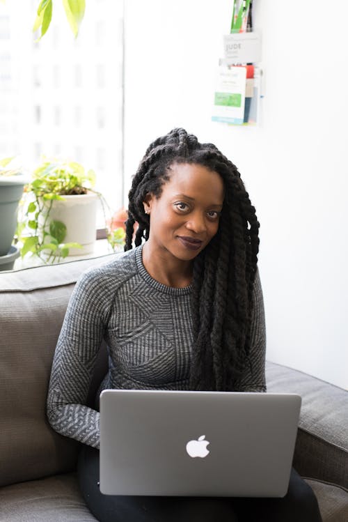 Femme Portant Un Pull Gris Avec Un Macbook Argenté Sur Ses Genoux