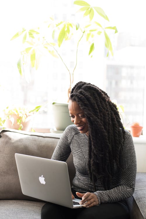 Mujer Sentada En Un Sofá Gris Mientras Sostiene Su Apple Macbook Air