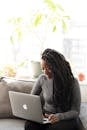 Woman Sittin on Gray Couch While Holding Her Apple Macbook Air