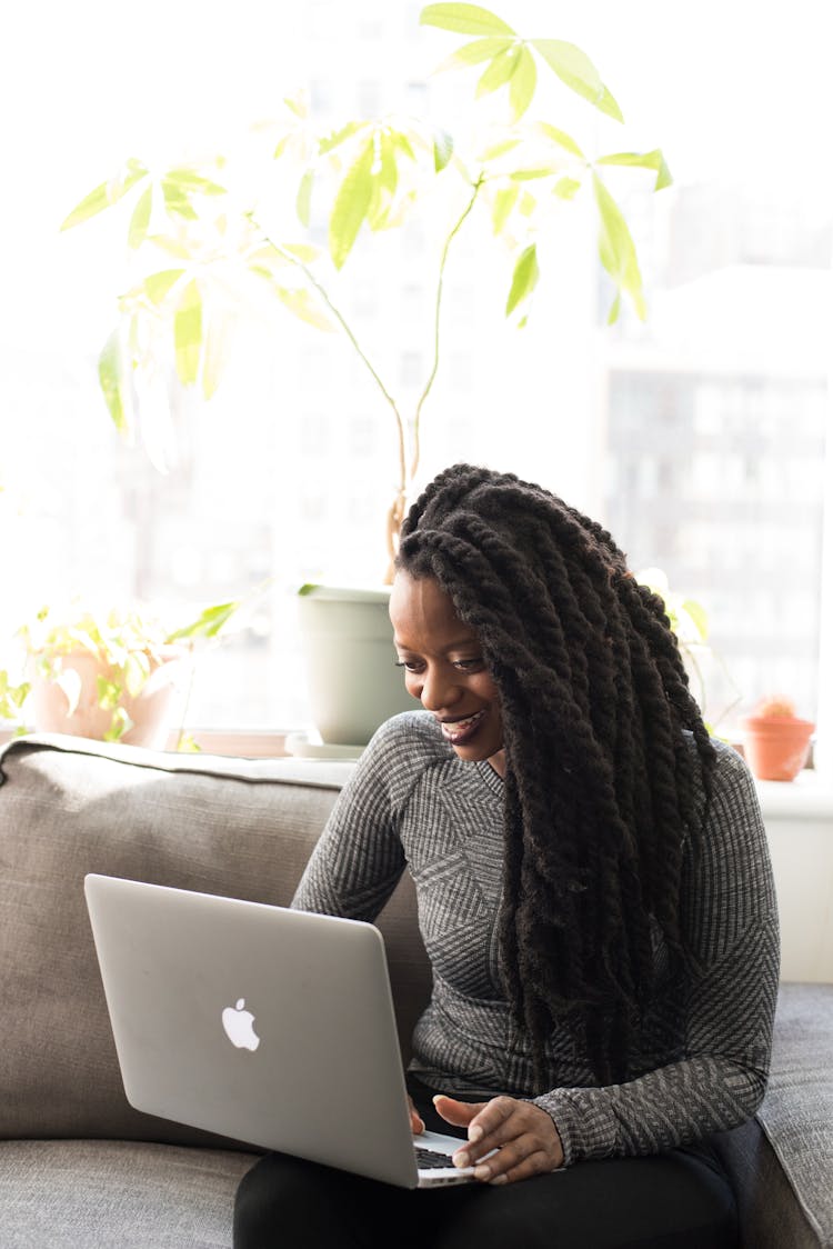 Woman Sittin On Gray Couch While Holding Her Apple Macbook Air