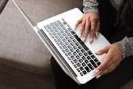 一位女士正专注地在笔记本电脑键盘上打字，展现着生产力与技术