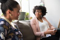 两位女商人坐在室内的沙发上，随意交谈着分享彼此的想法