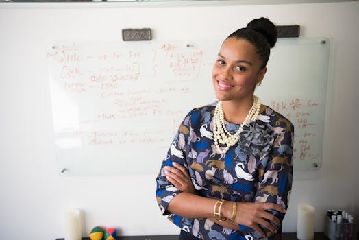 Smiling businesswoman standing in office with a background of a whiteboard, exuding confidence and charm.