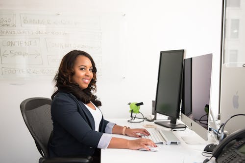 Woman in Professional Wear Seated in front of Monitor
