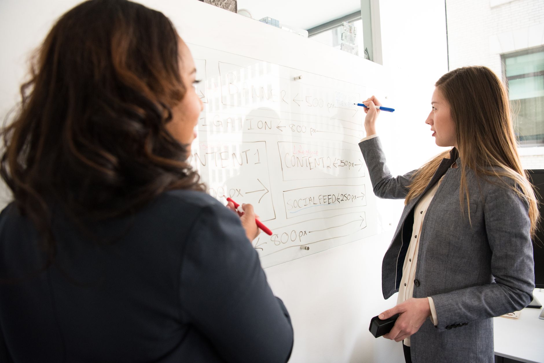 A boardroom whiteboard covered with options and tradeoff arrows drawn in marker