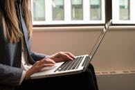 在现代室内办公环境中，一名女性正通过笔记本电脑远程工作