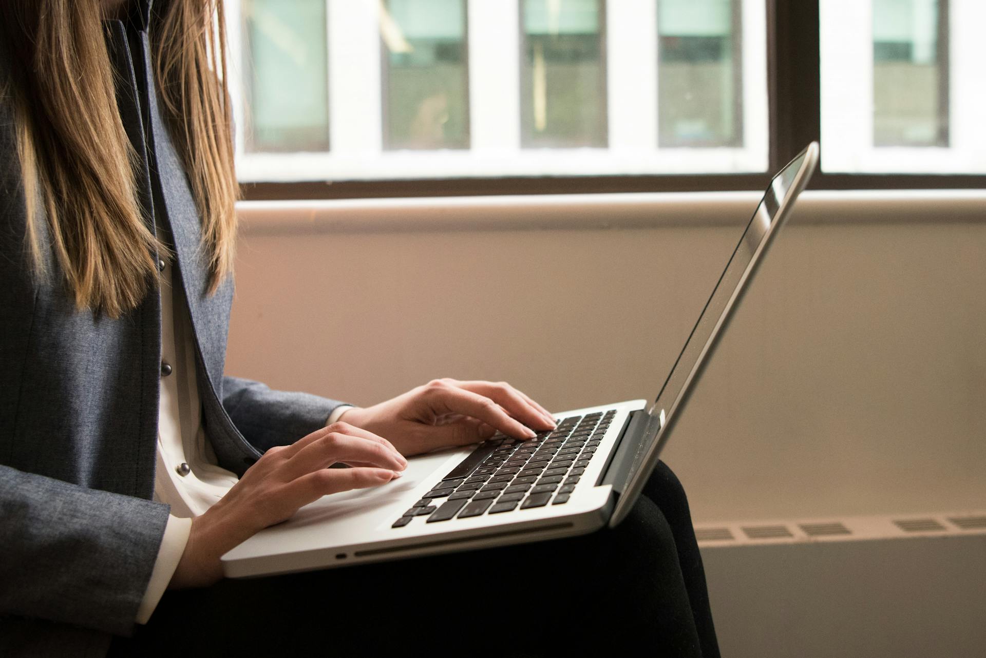 A woman working remotely on a laptop in a contemporary indoor office setting. Ideal for business or technology themes.