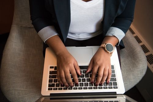 Free Woman typing on a laptop while seated indoors, showcasing technology and modern work habits. Stock Photo