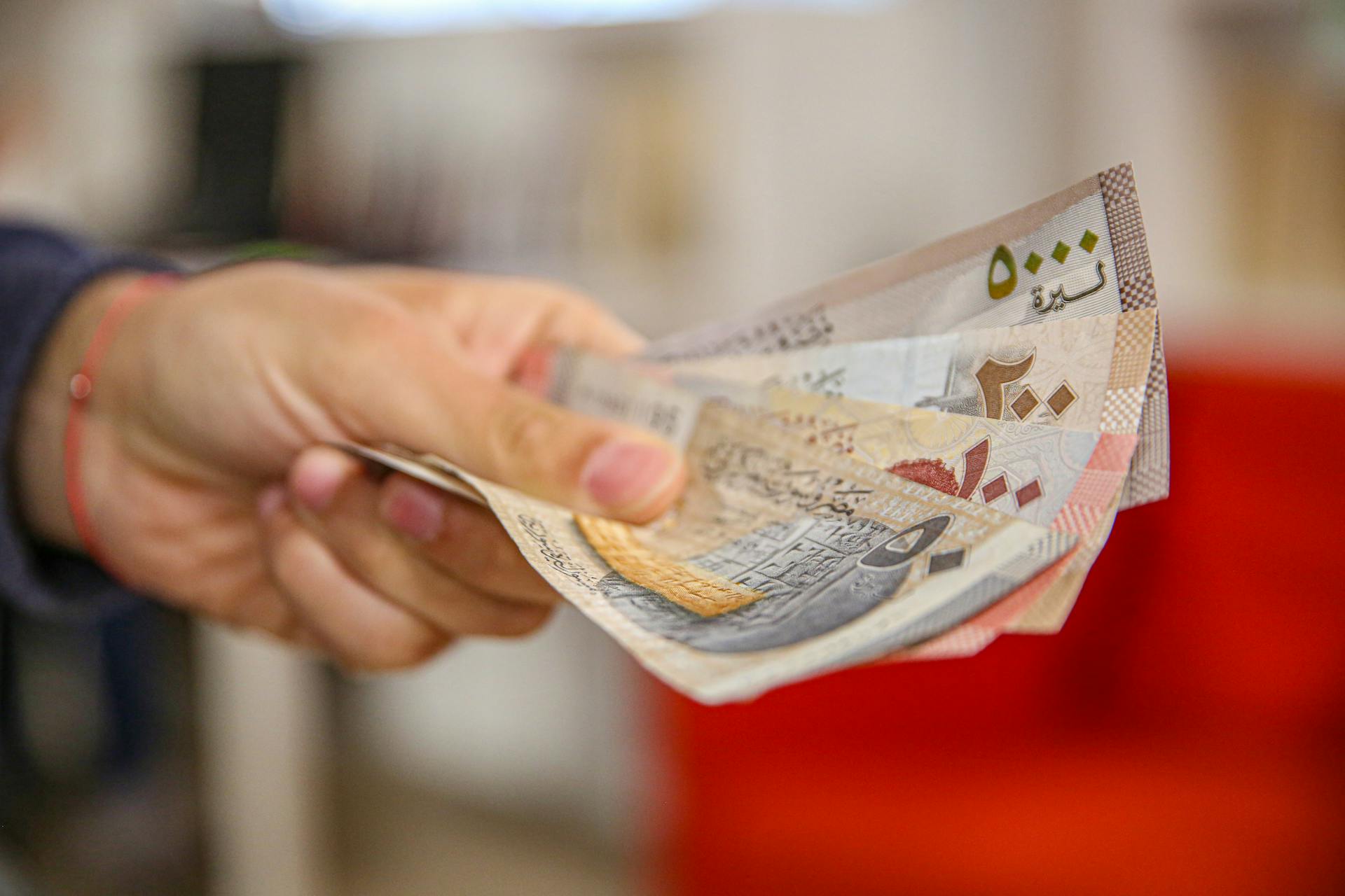 Close-up of a hand holding Jordanian dinar bills with a blurred background, highlighting currency exchange.