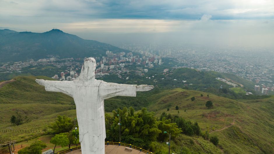Spectacular Spectacular Skydiving Experience with Transport from Medellin Review: The Ultimate Colombian Helicopter Adventure Review 2026 - Aerial shot of Christ the Redeemer statue overlooking a cityscape and lush green hills.