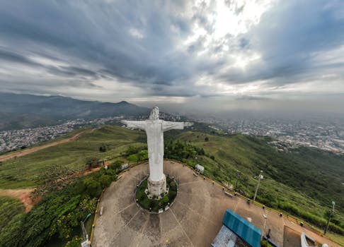 Breathtaking aerial view of the Cristo Rey statue overlooking Cali, Colombia surrounded by lush greenery and urban landscape.