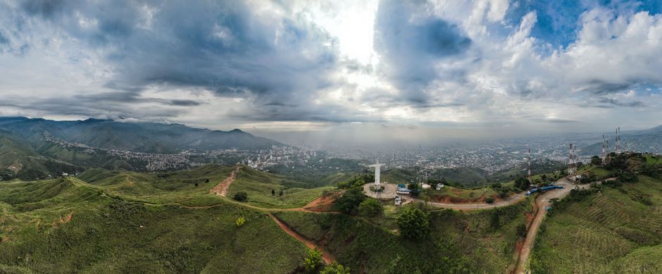 Incredible Private Tour of Guatapé by Helicopter and Boat Review: Colombia's Most Spectacular Dual Adventure Review 2026 - Stunning aerial panorama of Cali, Colombia featuring Cristo Rey statue under dramatic skies.