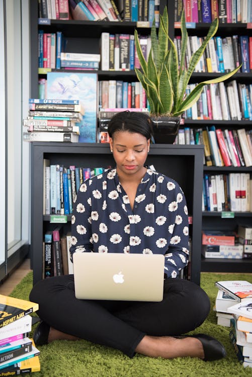 Mulher Sentada No Chão De Frente Para O Macbook Dourado