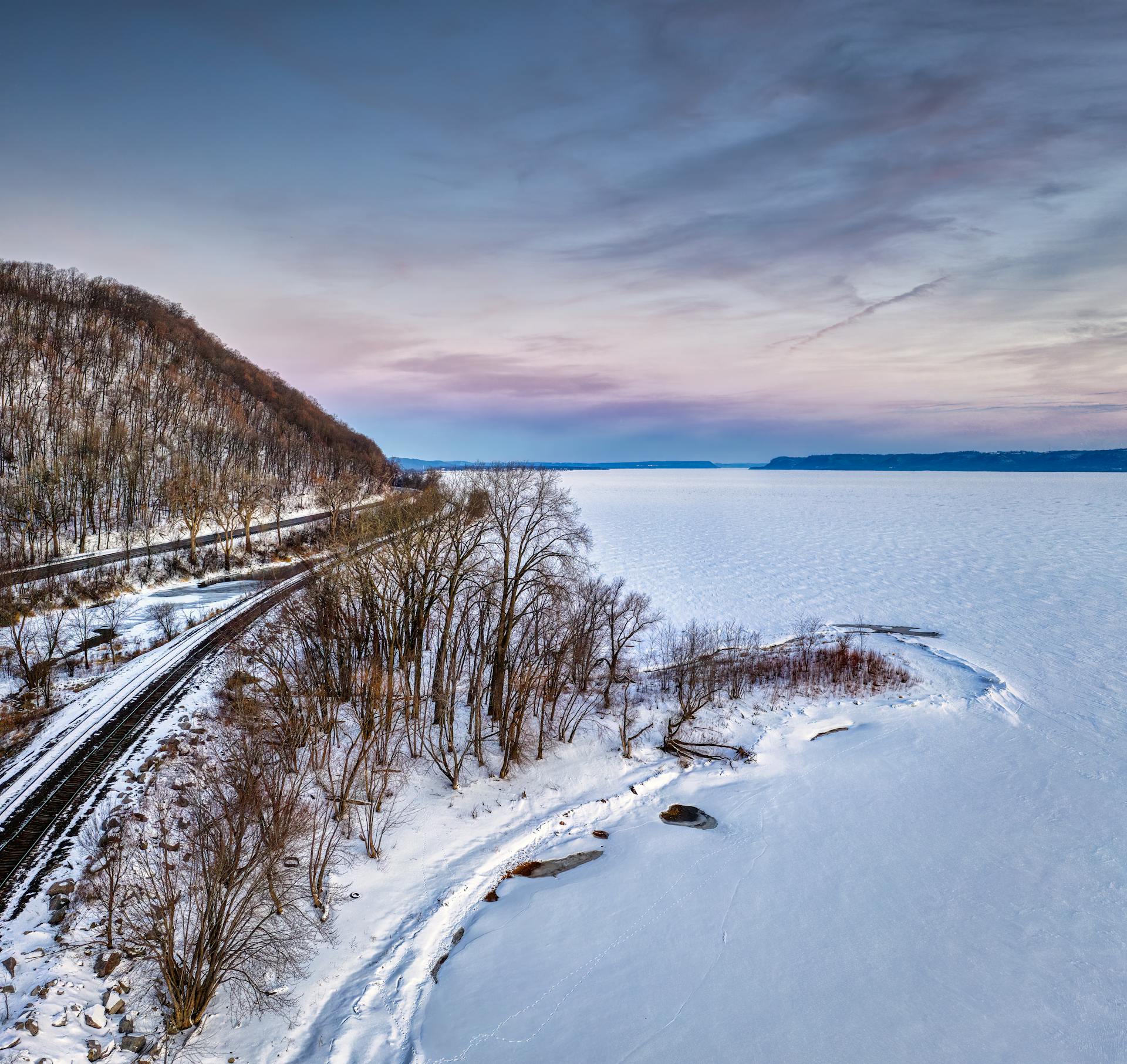 A stunning aerial view of a frozen lake and snowy landscape in Minnesota during winter.