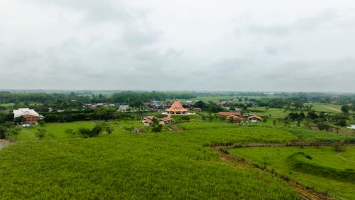 Free A scenic rural landscape featuring lush green fields and a village under an overcast sky. Stock Photo
