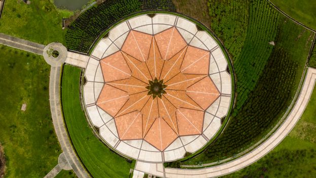 Top-down aerial view of a circular patterned garden structure with lush green surroundings.