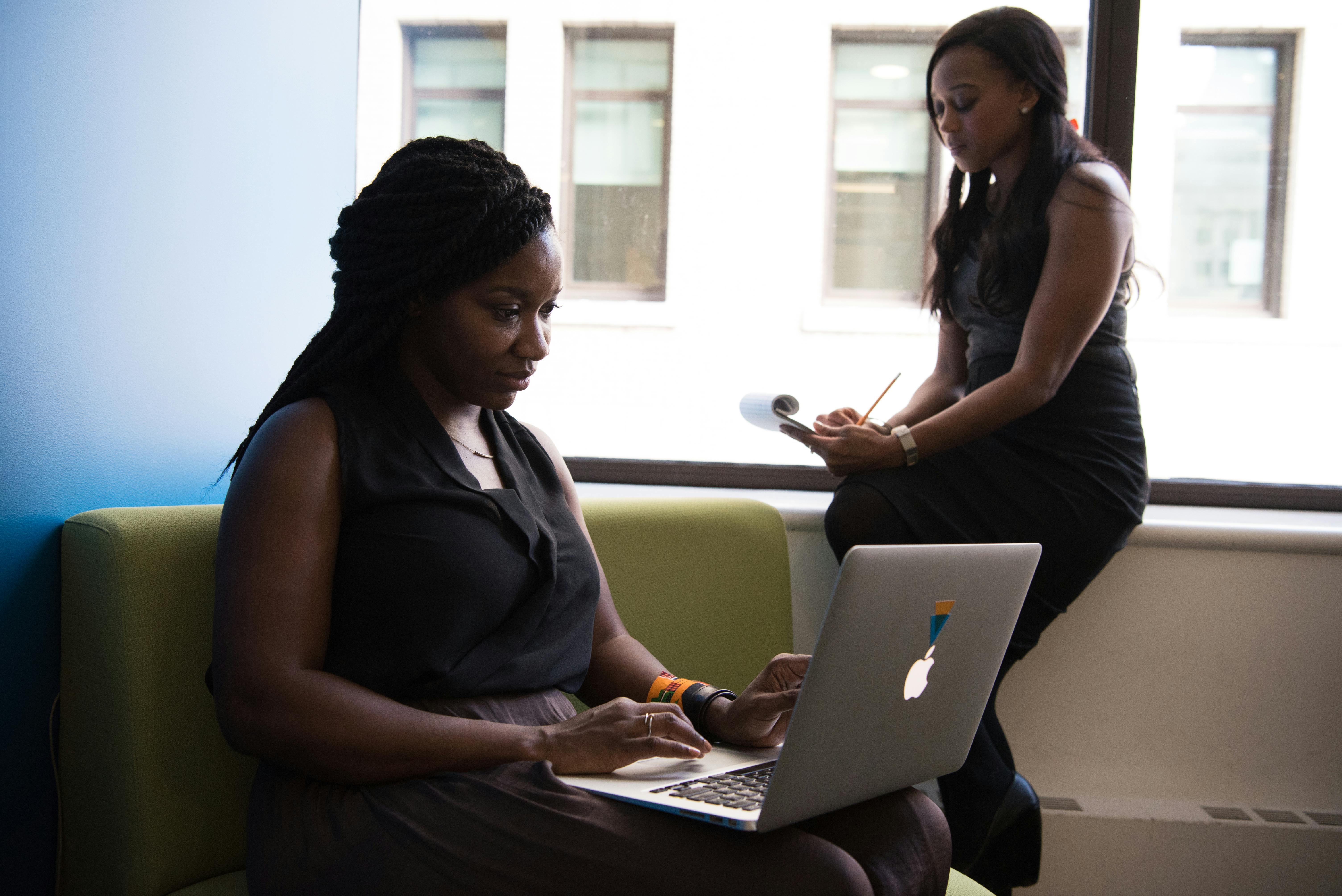 Woman Using Macbook Sitting on White Couch · Free Stock Photo