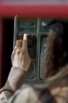 Close-up of a hand using a public phone outdoors in natural light.