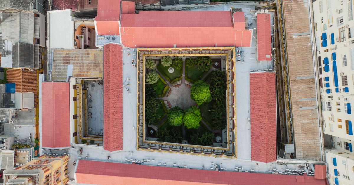 Aerial shot of an urban courtyard garden surrounded by buildings with red roofs.