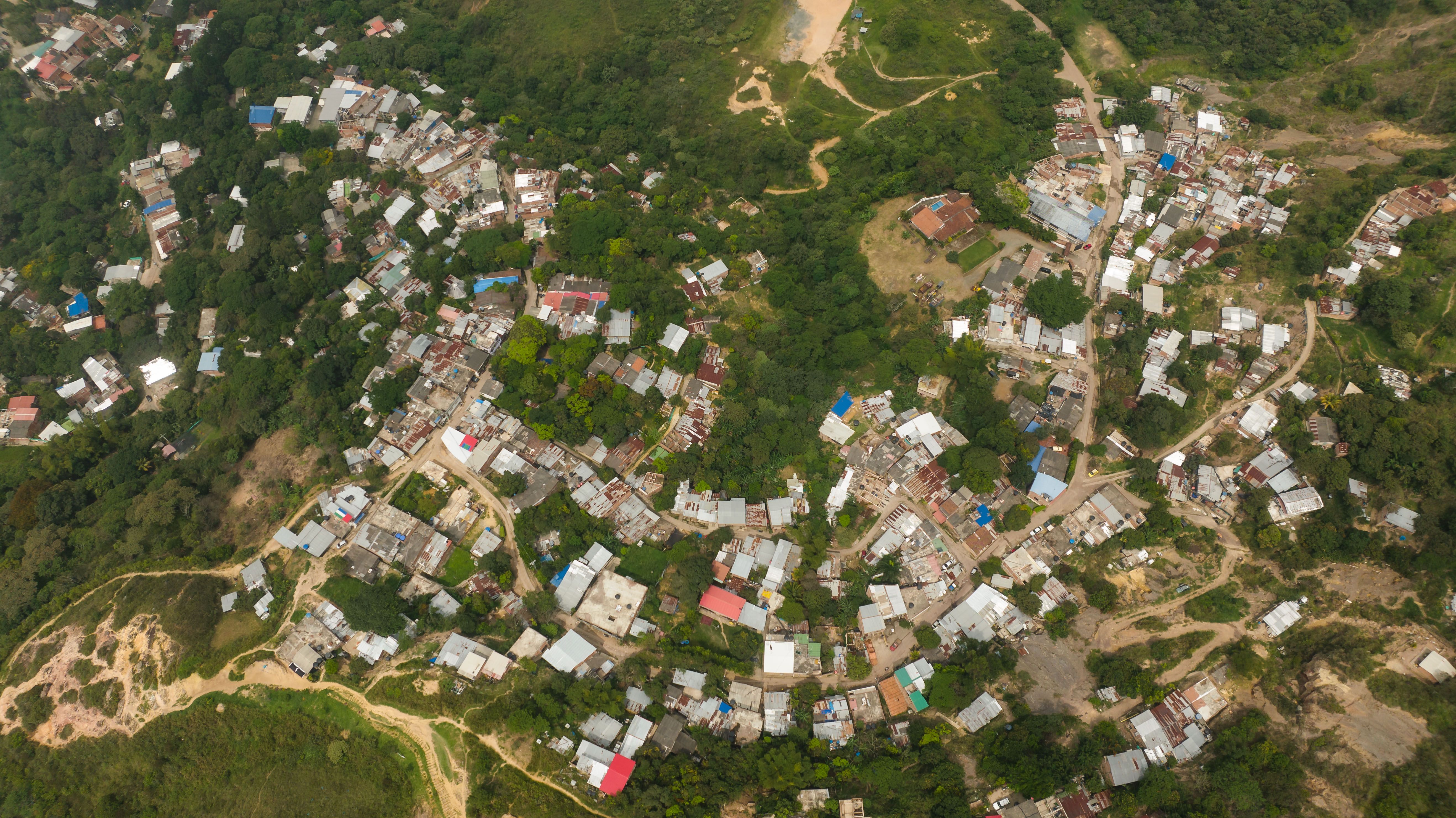 A top-down aerial shot showcasing a densely packed urban settlement amidst lush greenery, highlighting rural town life.